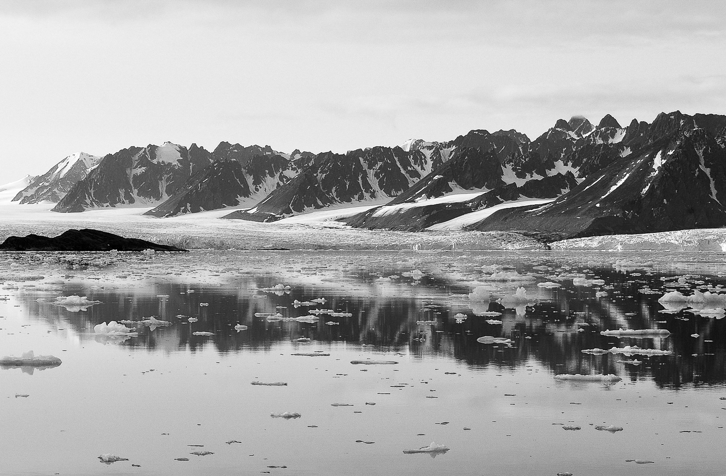 Photo de montagnes enneigÃ©es derriÃ¨re un lac sur lequel flotte de la glace.