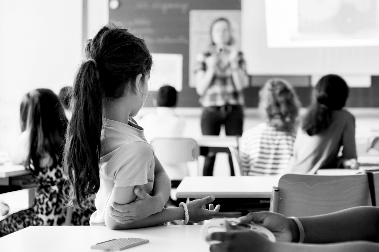 Image d'une classe, avec une enseigante donnant un cours Ã  l'arriÃ¨re-plan