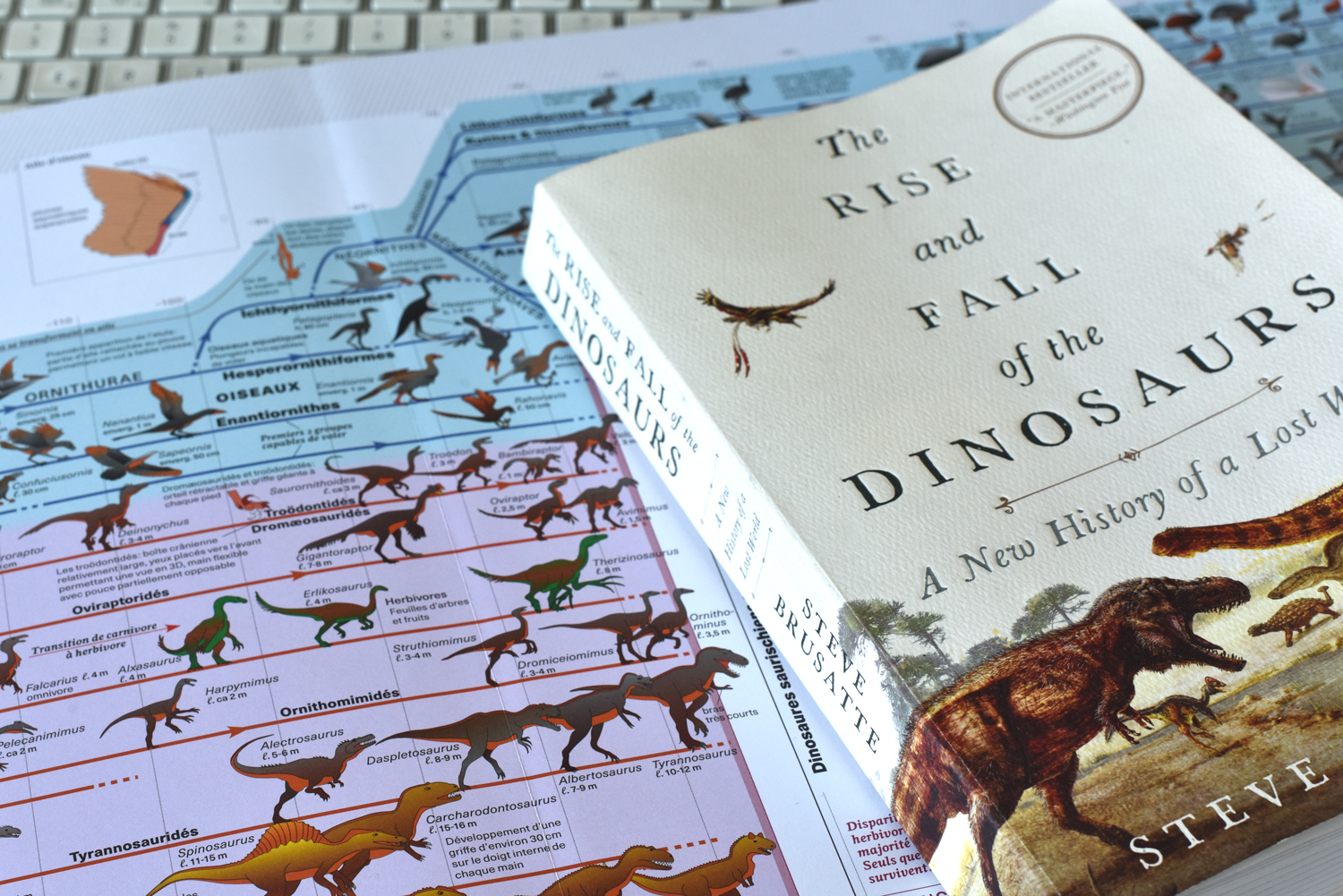 le livre Â«Le triomphe et la chute des dinosauresÂ» de Steve Bursatte posÃ© sur une planche de l'Atlas des vertÃ©brÃ©s