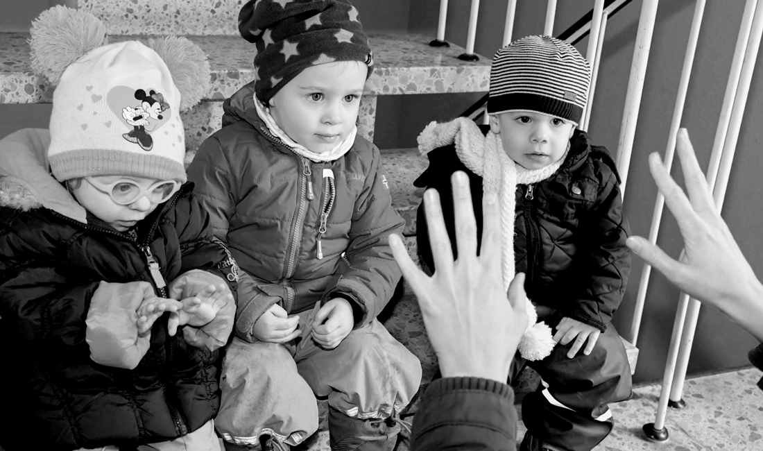 Des enfants, assis sur des escaliers, attendent de sortir